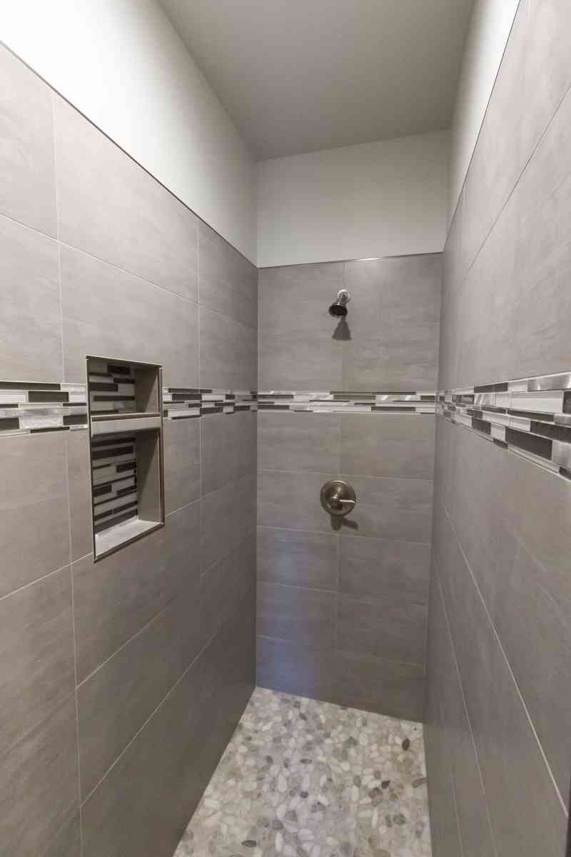 The tiled master shower and its beautiful pebble flooring.
