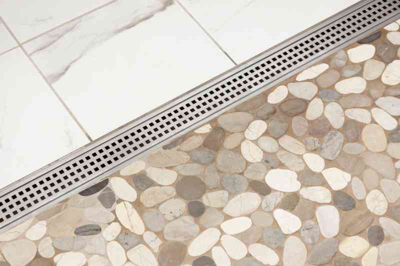 A detailed view of the horizontal shower drain and pebble tiling.