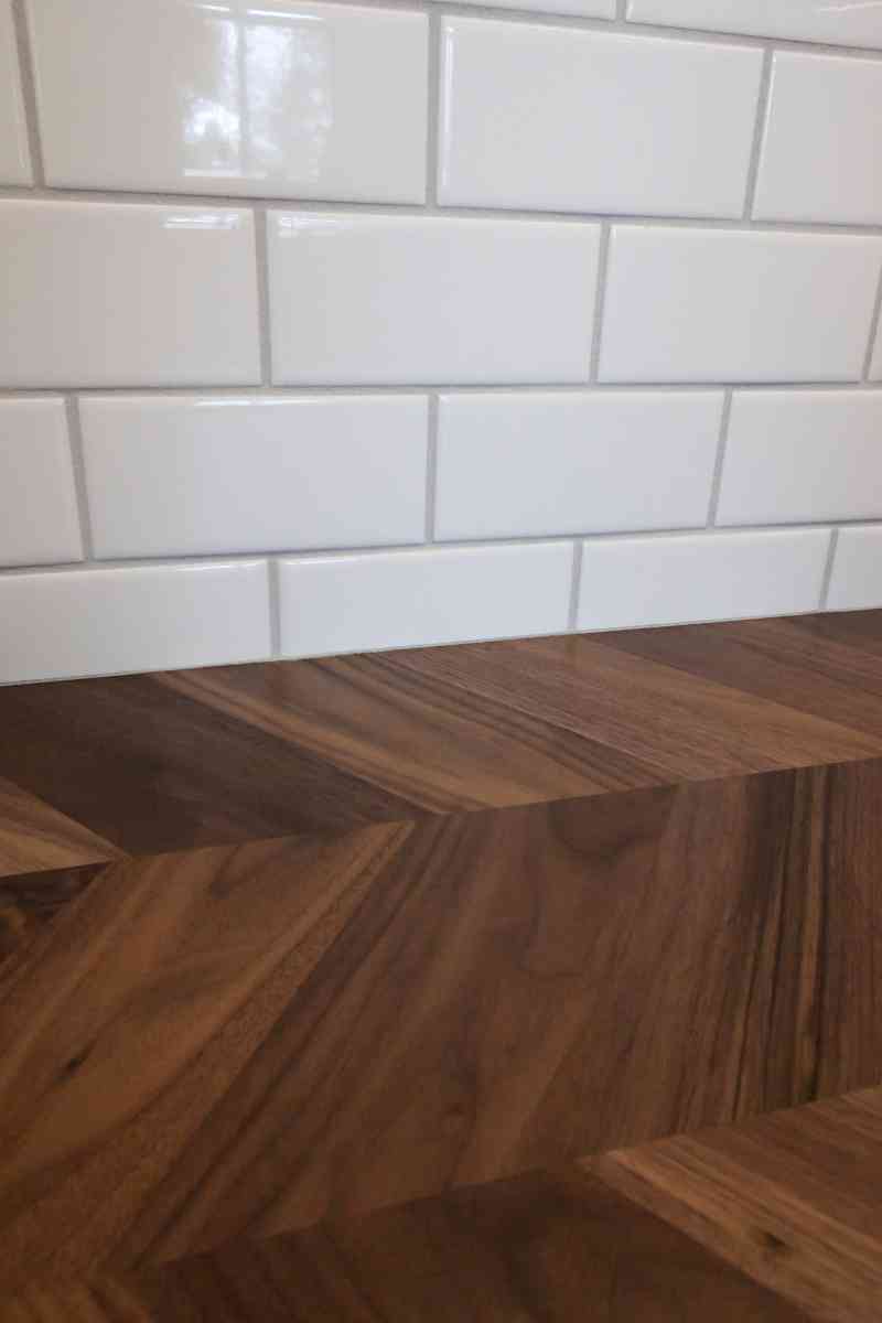 A detailed view of the white subway tile and gorgeous herringbone, wood countertops.